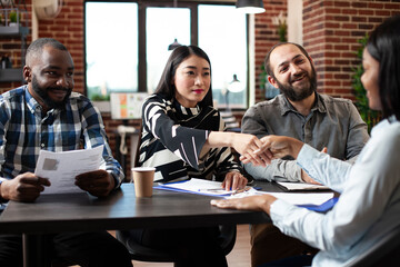 Asian recruiter handshaking african american candidate, welcoming her to the job interview meeting. Human resources team sitting and greeting black woman at office desk, starting the hiring process.