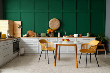 Interior of modern kitchen with white counters and dining table