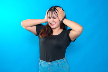 A young Asian woman smiling with her hands on her head, expressing happiness and excitement. Her...