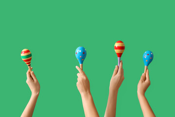 Female hands holding maracas on green background