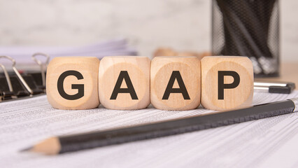 Wooden blocks spelling "GAAP" on financial documents, representing Generally Accepted Accounting Principles