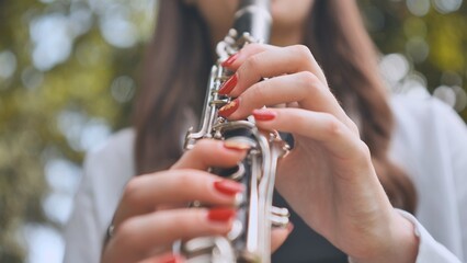Close up of a musician's hands playing a clarinet outdoors, showcasing musical talent and passion...