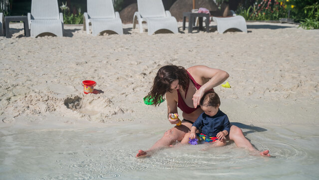 Caucasian woman applies sunscreen to her one-year-old son's skin. 