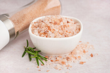 Bowl of Himalayan pink salt and rosemary on white background