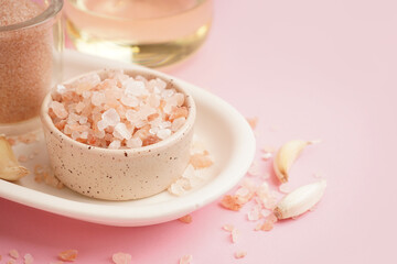 Bowl with Himalayan pink salt and garlic on pink background