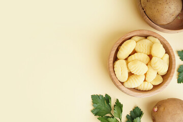 Wooden bowl with tasty gnocchi and parsley on beige background