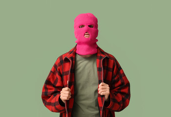 Handsome young man in balaclava on green background
