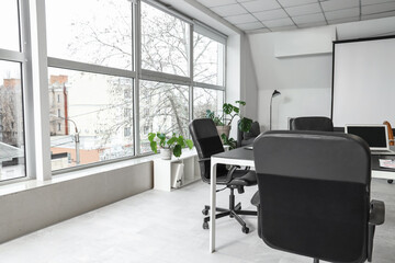 Interior of stylish conference hall with table, screen board and window