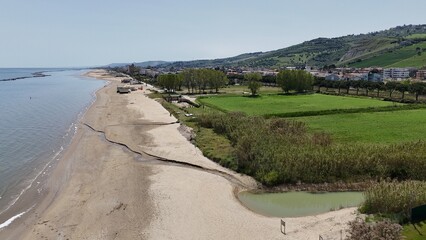 An aerial view of a wide sandy beach and coastline in Roseto Degli Abruzzi, Italy, with a green...