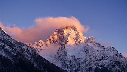 A majestic snowy mountain peak illuminated by the first light of dawn, with clouds wrapping around the summit