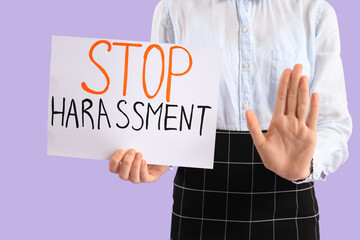 Business woman holding paper with text STOP HARASSMENT on lilac background, closeup