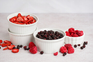 Bowls with tasty freeze-dried berries on light background