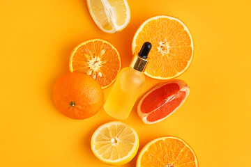 Bottle of essential oil and ripe citrus fruits on color background