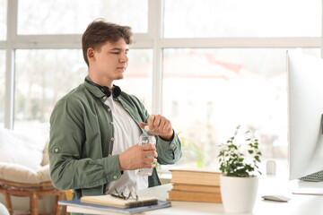 Male student with bottle of water studying online at home