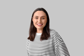 Fototapeta premium Smiling young woman on grey background