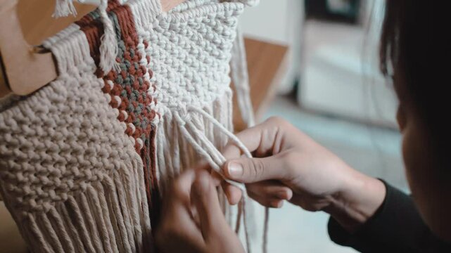 Video of a woman making macrame at home. Profile and close-up shots.