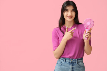 Young woman with mini fan on pink background