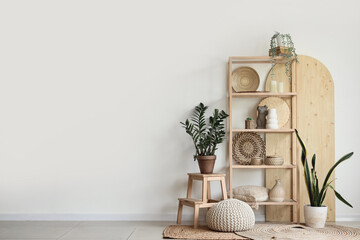 Shelving unit with statuettes and houseplants near white wall in room