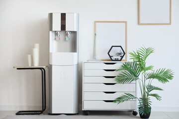 Interior of light office with water cooler and drawers