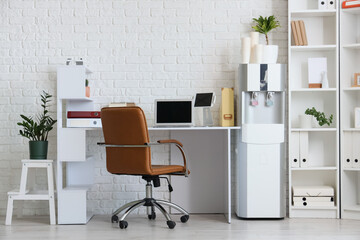 Interior of office with workplace, shelf unit and water cooler