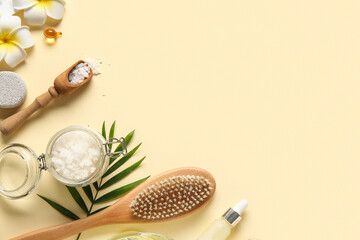 Spa composition with natural body scrub, massage brush and tropical flowers on color background