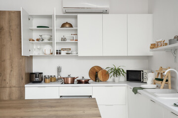 Interior of modern kitchen with counters, cupboards and utensils