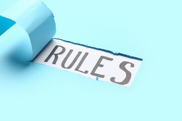 Word RULES visible through torn blue paper, closeup