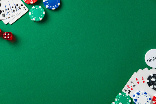 Green poker table flat lay with cards, chips, dice, and dealer button. Gambling or casino background concept with empty center copy space.