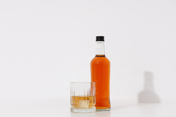 Bottle and glass of cold rum on white background