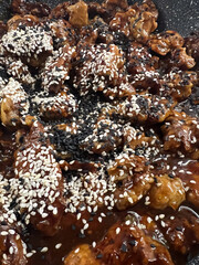 Enjoy Sesame Chicken in Savory Sauce with White and Black Seeds for added flavor and texture