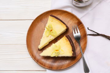Plate with pieces of sweet vanilla cheesecake on white wooden background