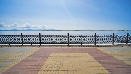 Scenic view of an embankment featuring decorative metal railing, overlooking a calm river under a...