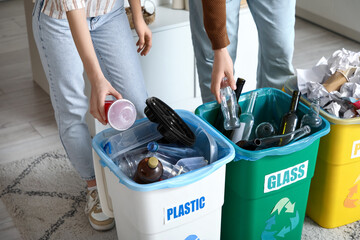 Young couple sorting rubbish in garbage bins at home, closeup. Global Recycling Day