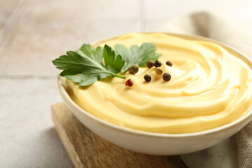 Delicious mayonnaise sauce with parsley and peppercorns in bowl on light table, closeup