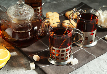 Glasses of tea in metal holders served on grey textured table, closeup