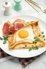 Delicious crepe with egg, bacon, arugula and green peas on white marble table, closeup