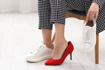 Woman changing shoes on chair indoors, closeup. Space for text