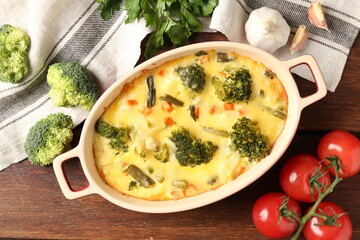 Delicious vegetable casserole and ingredients on wooden table, flat lay