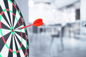 Targeting and business success. Dart sticking in center of dartboard in office, closeup