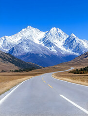 Naklejka premium Scenic asphalt road curves through vast plains towards majestic snow-capped mountains under a vibrant blue sky. generative ai