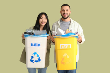 Young couple with sorted rubbish in garbage bins on green background. Global Recycling Day