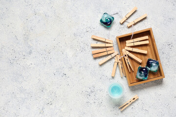 Storage box with wooden clothespins and gel capsules on grunge white background