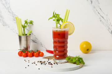 Glass of bloody mary cocktail and ingredients on white background