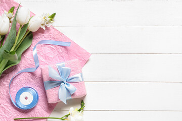 Pink gift box with flowers, wrapping paper and ribbon on white wooden background. International Women's Day