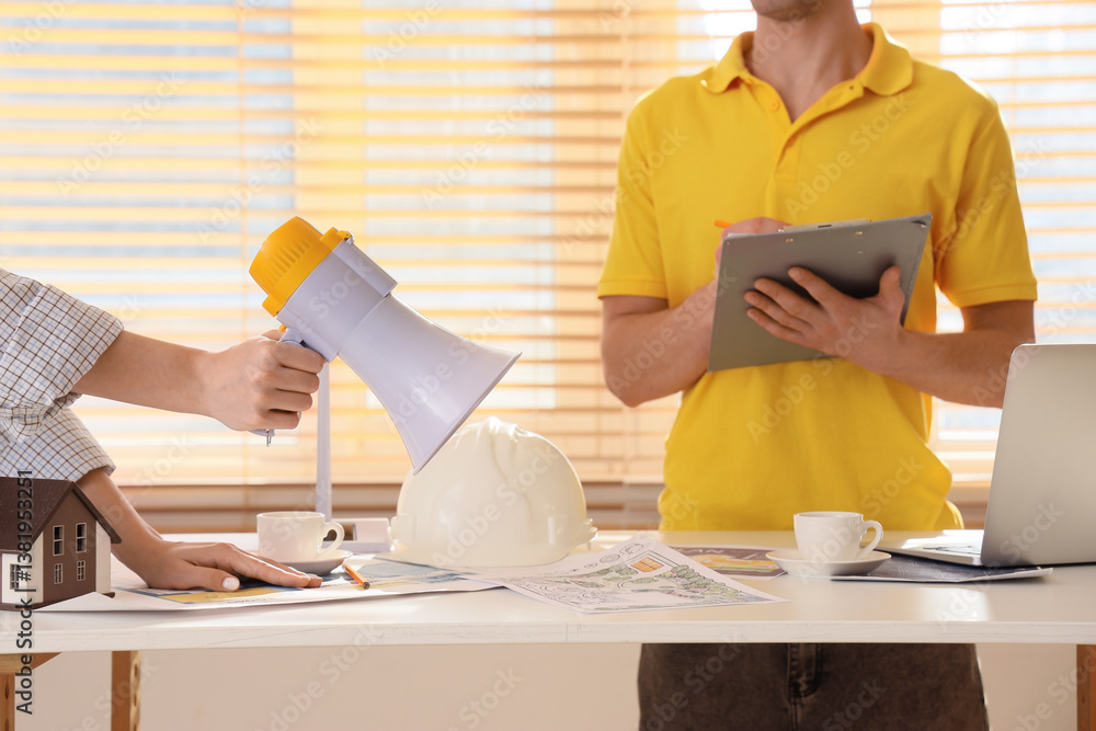 Poster constructors with megaphone working at table in office