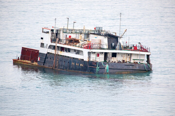 Rusty old cargo ship floating on calm sea waters, showing signs of wear with faded paint and...