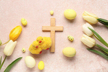 Wooden cross with painted eggs, chicks and tulip flowers on pink grunge background. Easter celebration