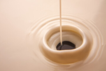 Dynamic shot of milk pouring into a creamy pool, forming a swirling vortex with ripples. Ideal for...