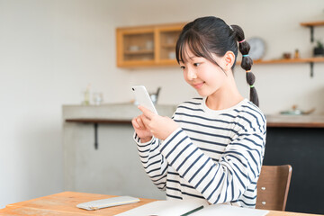家でスマホを使いながら勉強する小学生,中学生の女の子,子供
