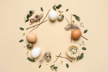 Frame made from Easter eggs, feathers and leaves on beige background